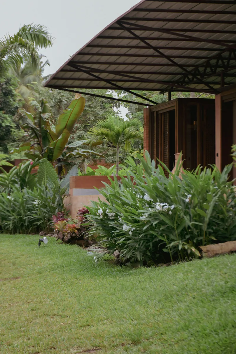 Garden courtyard with planted beds of palms and tropical greenery beneath a steel-framed overhang