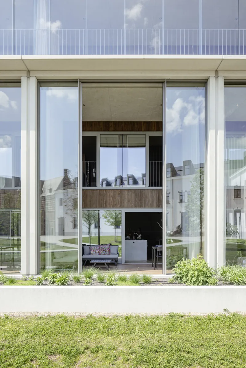 Ground floor terrace with full-height glazing and white structural columns framing views to the courtyard beyond