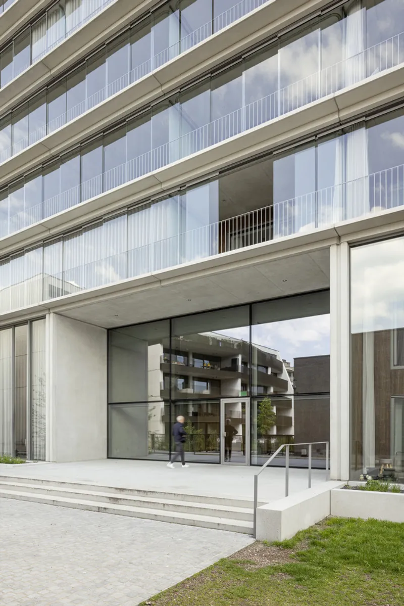 Ground floor entrance with wide steps and floor-to-ceiling glass doors beneath alternating ribbons of glass and concrete balconies