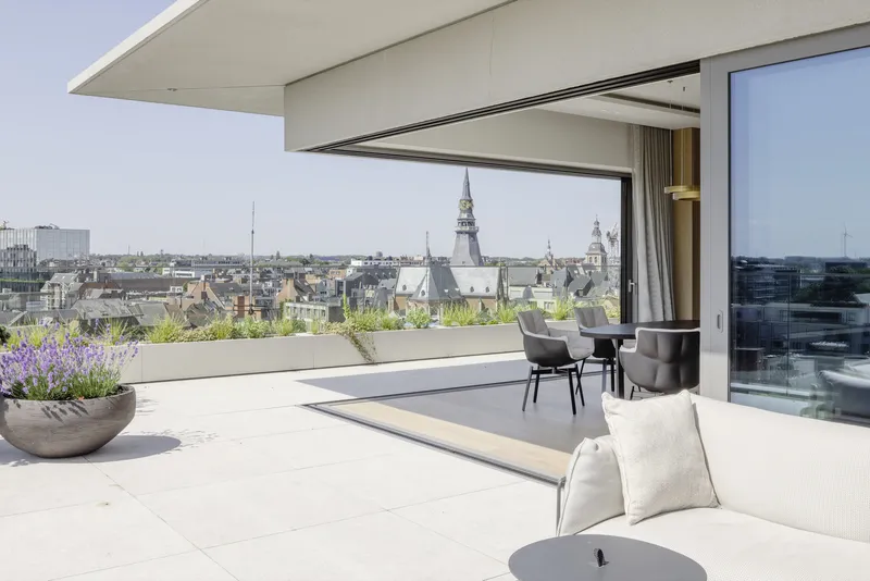 Rooftop terrace with motorized canopy opening and planted bed overlooking historic church spires
