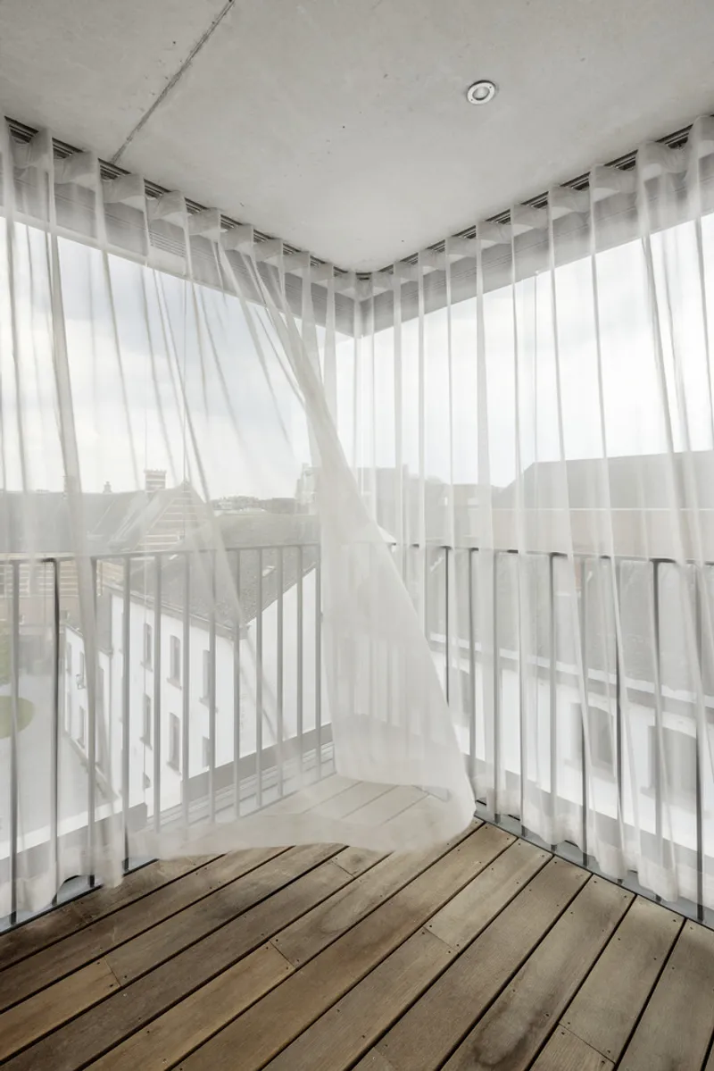 Corner balcony with timber decking and sheer curtains billowing in the breeze