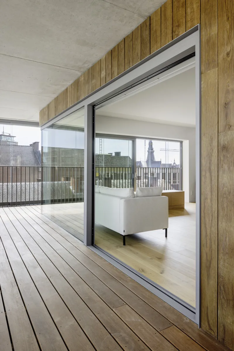 Sliding glass door threshold between timber deck and interior space with oak wall cladding