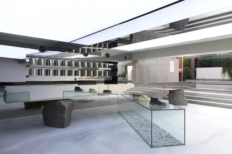 Interior retail space with glass display platforms over gravel beds and wide concrete steps leading upward