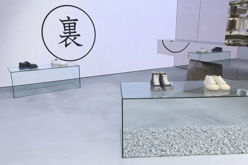 Low glass display plinths in a white retail interior with a circular graphic on the wall