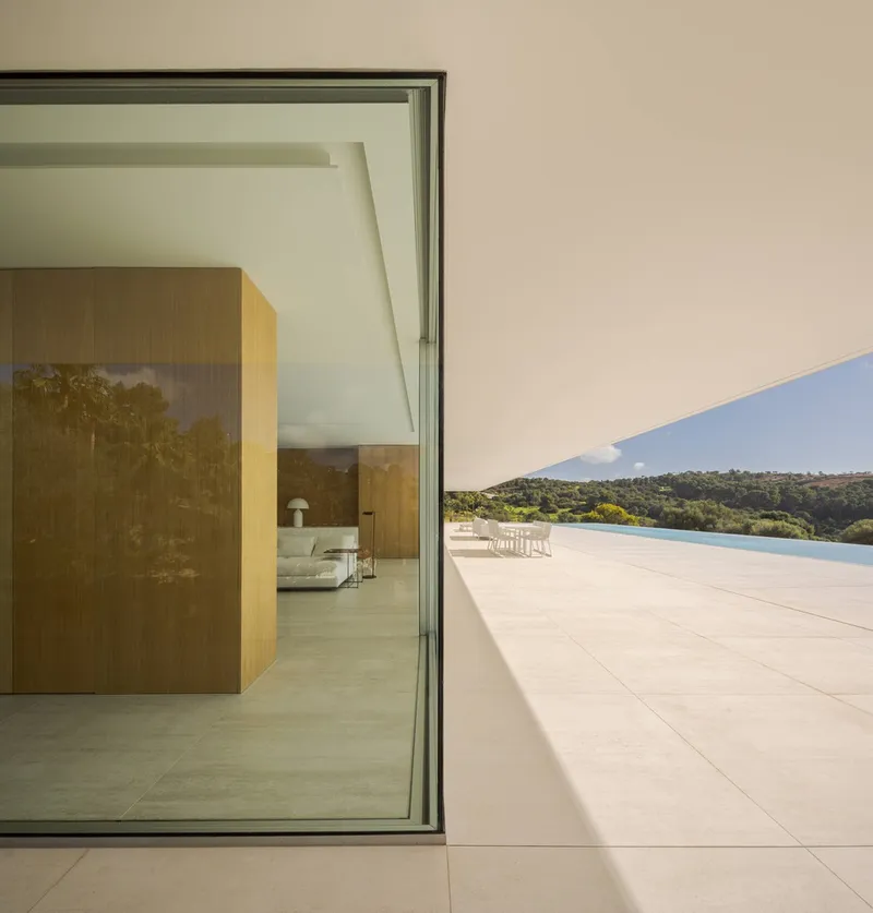 Corner threshold between interior tiled floor and exterior terrace overlooking distant forested hills and pool