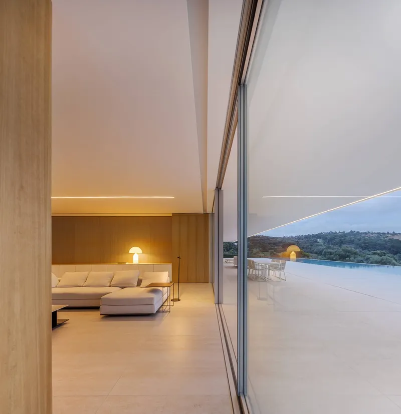 Interior living space with timber cladding and linear ceiling lighting at dusk