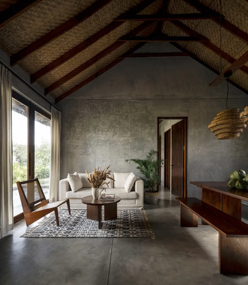 Living room with exposed timber roof trusses and woven ceiling panels above polished concrete floors