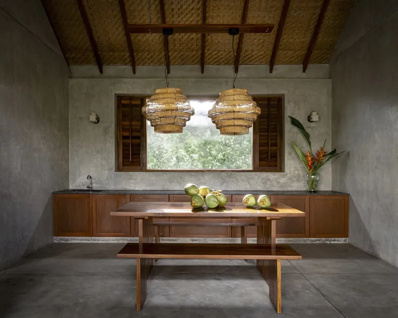 Kitchen with timber cabinetry and paired woven pendants centered beneath a horizontal louvered window