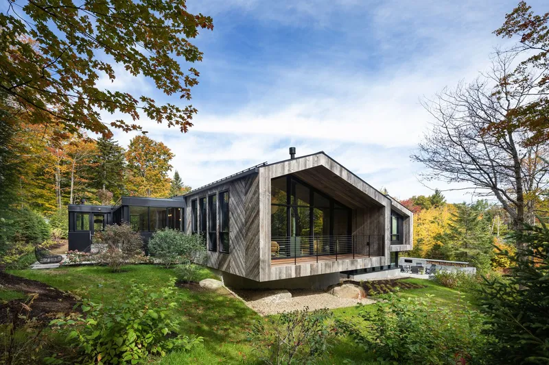 Exterior view of the timber-clad volume with herringbone facade pattern set among fall foliage