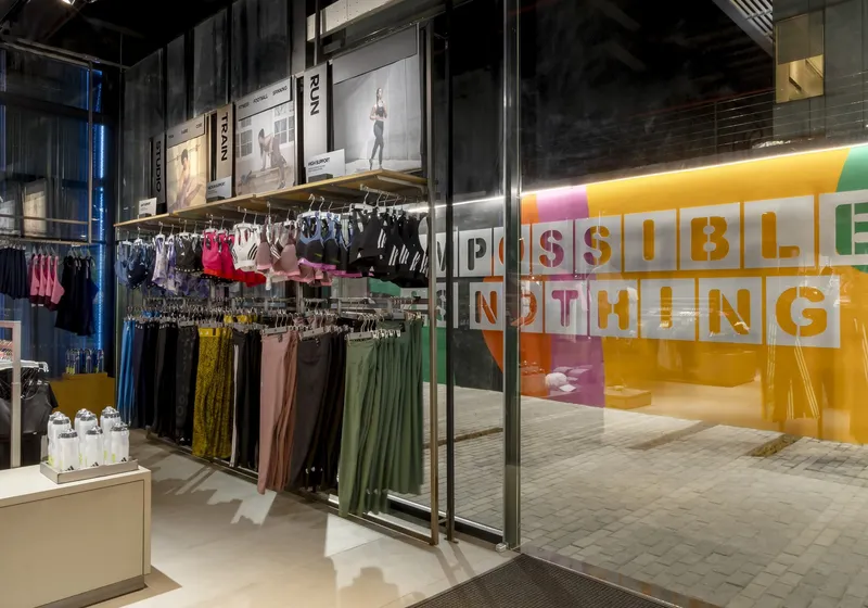 Retail interior with clothing racks viewed through glass doors toward the graphic-painted courtyard beyond