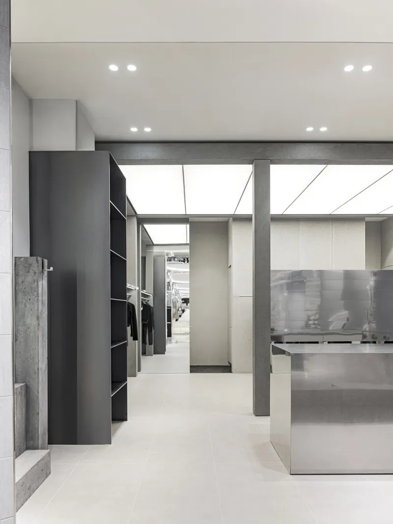 Illuminated skylight above concrete columns and a translucent glass partition in the retail space