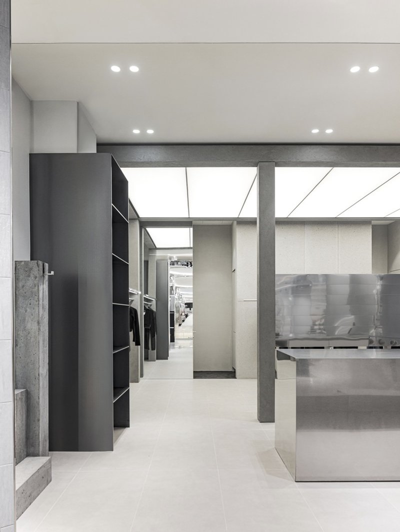 Illuminated skylight above concrete columns and a translucent glass partition in the retail space