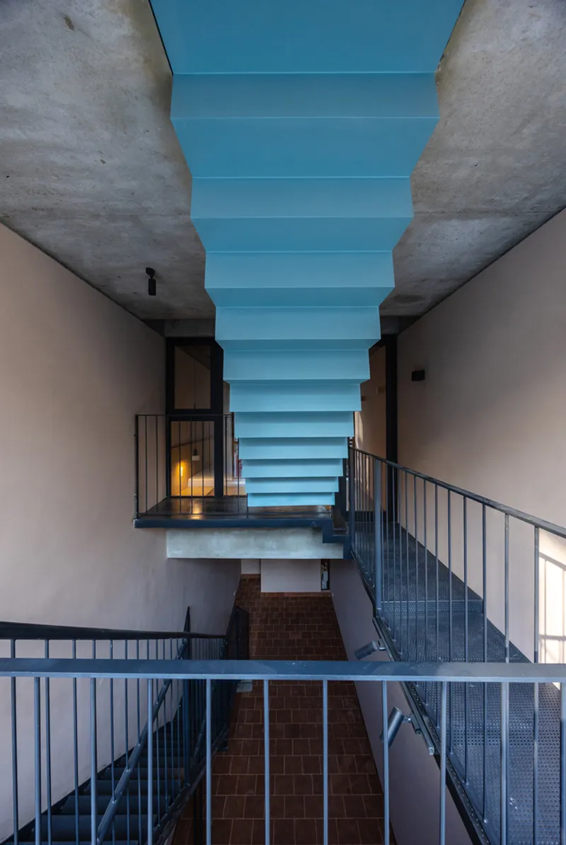Multi-level atrium with steel railings and stacked horizontal skylights running through exposed concrete walls