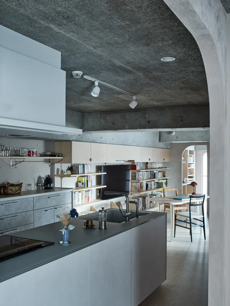 Kitchen with vaulted concrete ceiling, island countertop and open shelving under track lighting