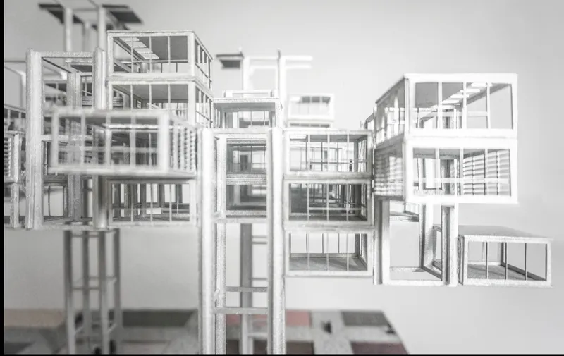 Physical model showing white framed volumes stacked in clusters with open structural frameworks