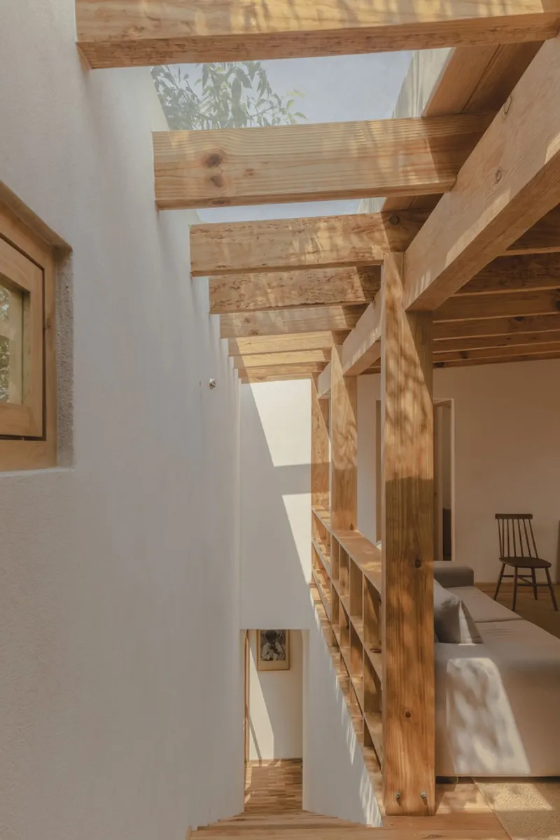 View up through double-height space showing exposed timber beams and joists with filtered daylight from skylights