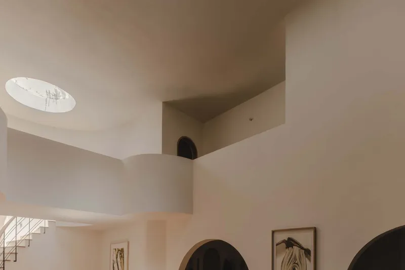 Curved balcony edge overlooking double-height space with circular skylight and arched doorways below