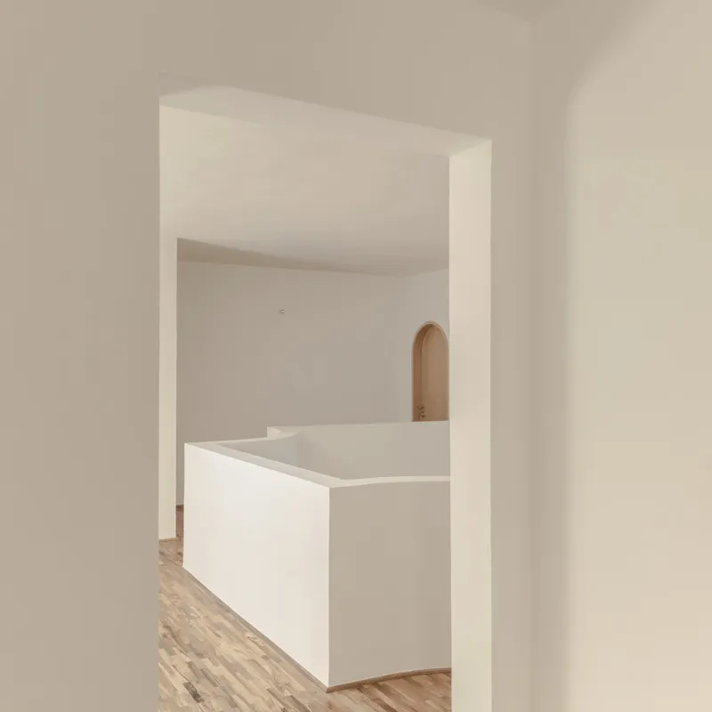 White plastered interior with a timber-arched doorway and light wood flooring visible through a wide opening
