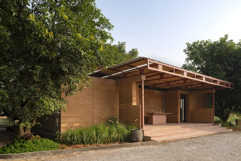 Side elevation showing the cantilevered roof structure, timber cladding and planted landscape bed