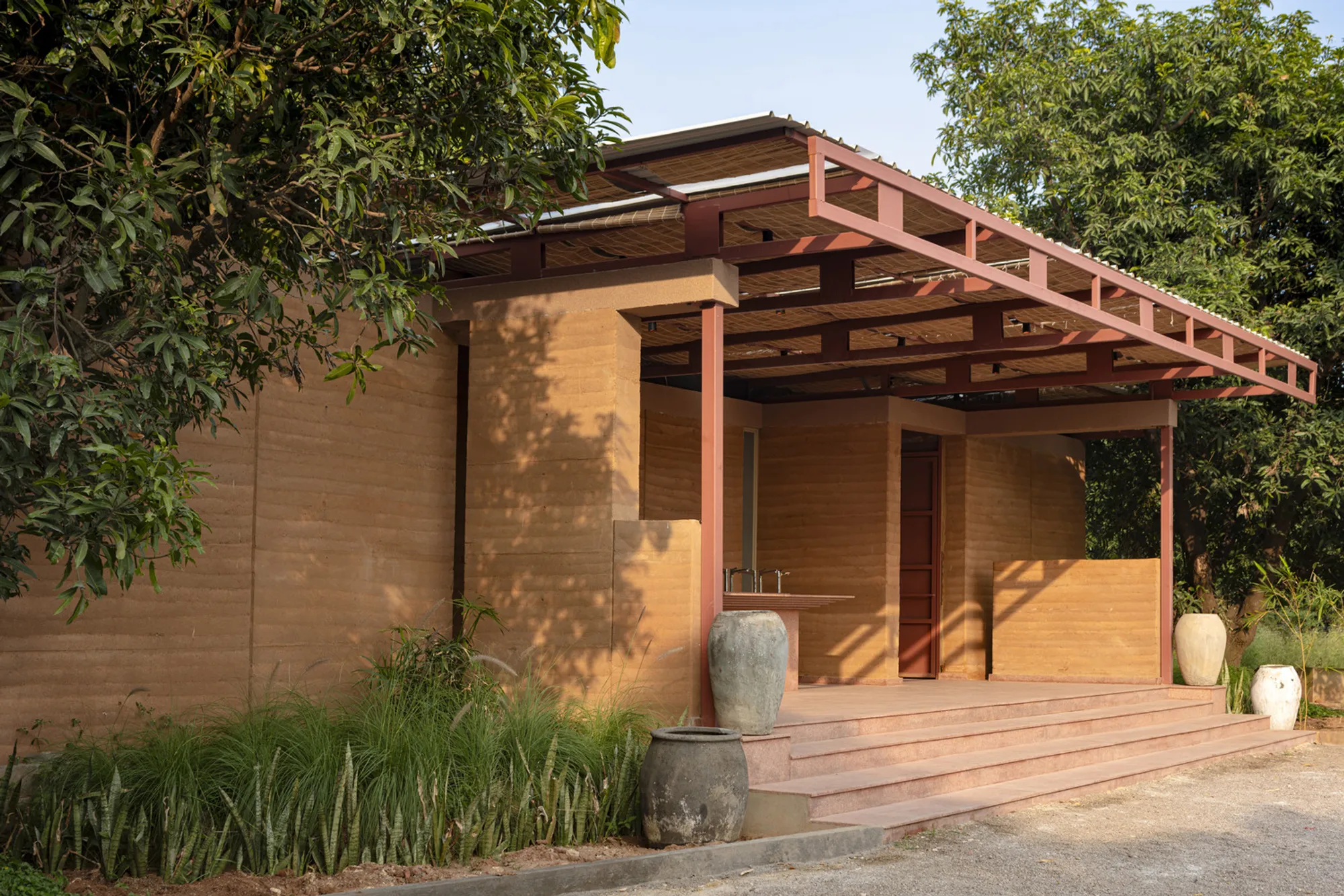 NaaV Studio Builds a Rammed Earth Restroom That Disappears into a Hyderabad Mango Grove