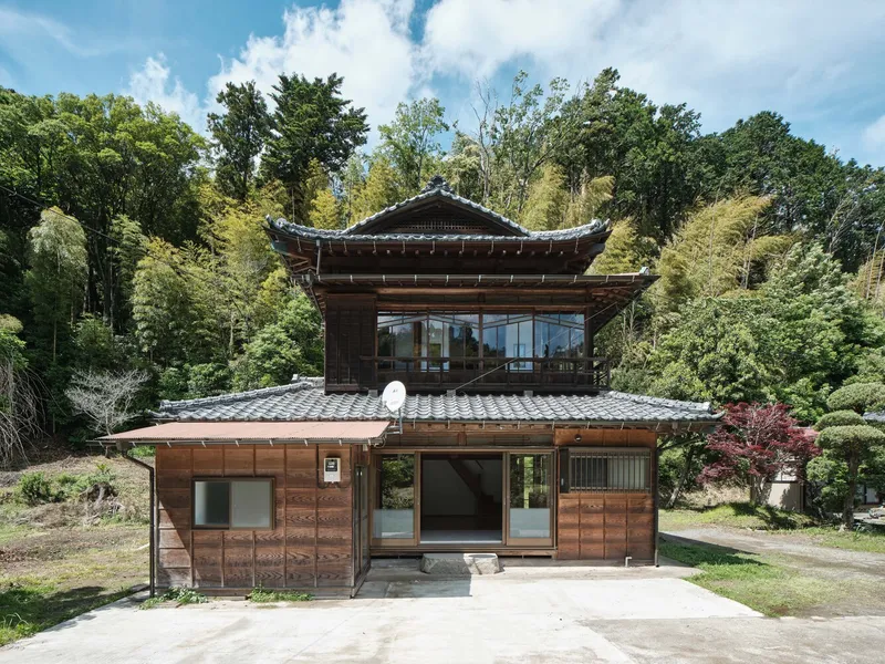 Front facade with timber cladding and glazed upper level beneath a curved tile roof edge