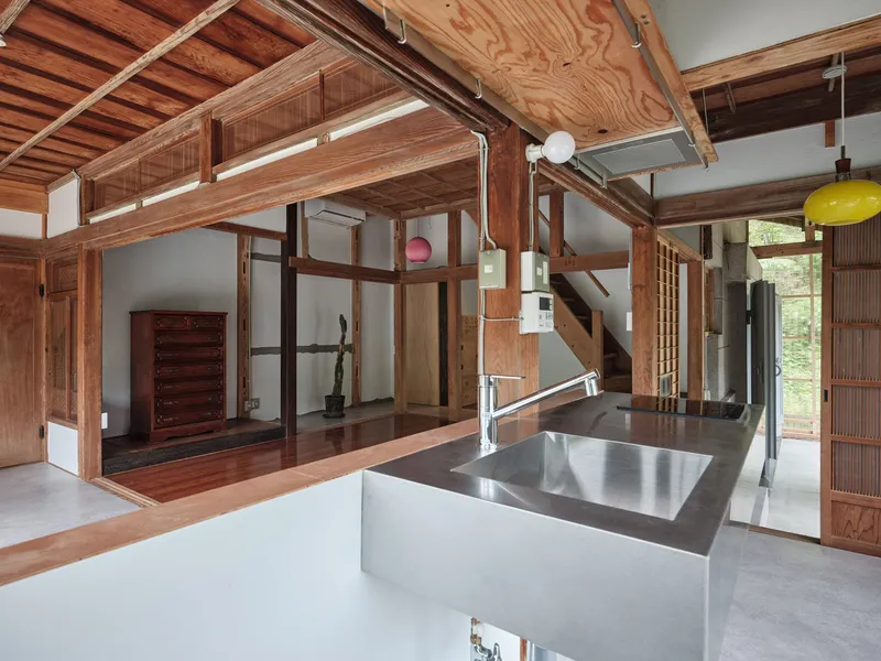 Kitchen island with stainless steel countertop beneath timber ceiling and yellow pendant light