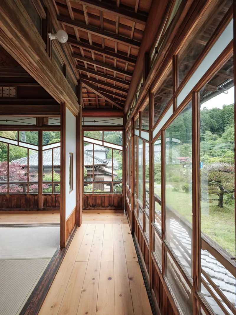 Timber-framed corridor with sliding glass panels overlooking garden and pond