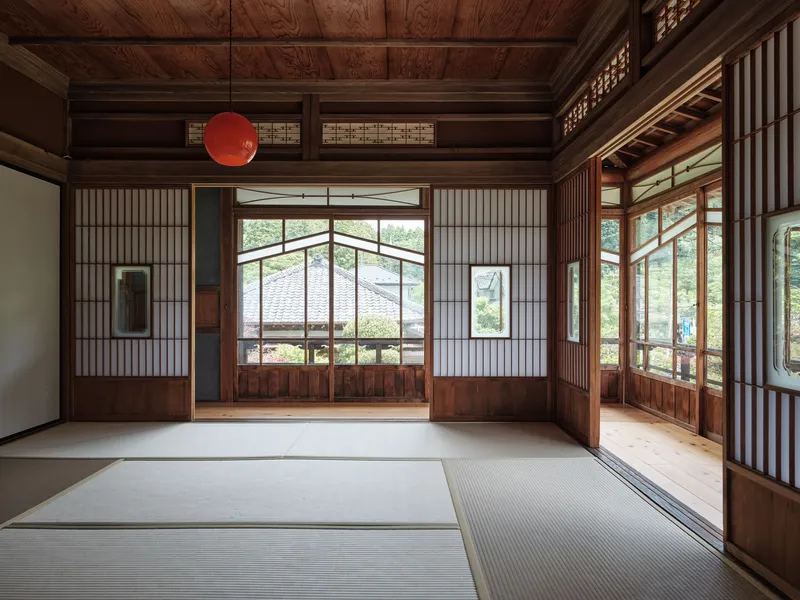 Tatami room with coffered wood ceiling, shoji screens and a red pendant light overlooking a garden