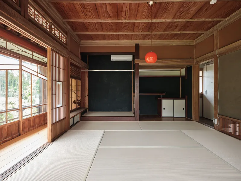 Interior tatami room with exposed timber framing, a tokonoma alcove and red pendant light