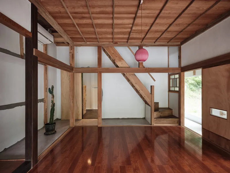 Interior view showing exposed timber frame and coffered ceiling above polished wood floors with a pink pendant light
