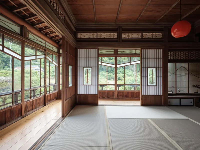 Tatami mat room with sliding shoji screens and transom windows overlooking a green landscape