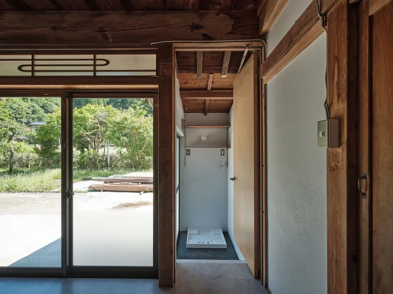 View through timber-framed doorway to entrance vestibule and garden beyond glazed doors