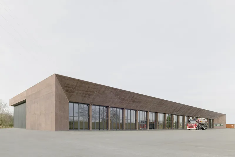 Long elevation showing the concrete structure with glazed bays and fire trucks under canopy