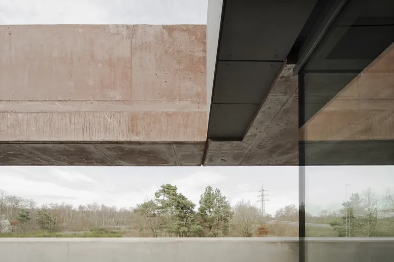 Cantilevered concrete overhang framing a view of bare trees and transmission towers in fog