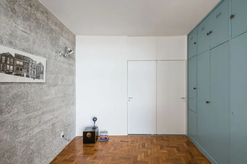 Interior room showing flush white door set in wall beside teal built-in storage and concrete feature wall