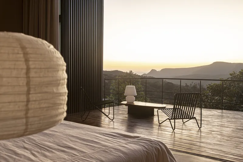 Timber deck terrace with glass railing overlooking mountains at sunset