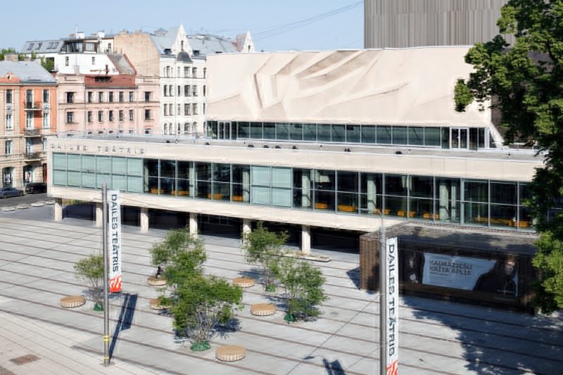 Two-story glass facade with concrete columns and pleated canopy above the plaza
