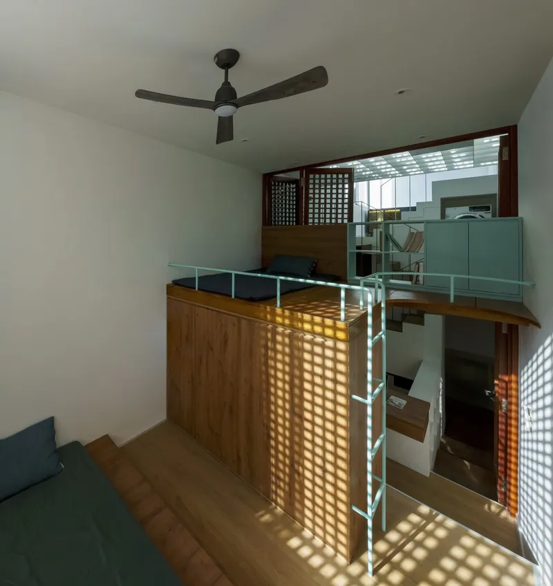Upper level mezzanine with timber volume and screened openings casting grid patterns of sunlight
