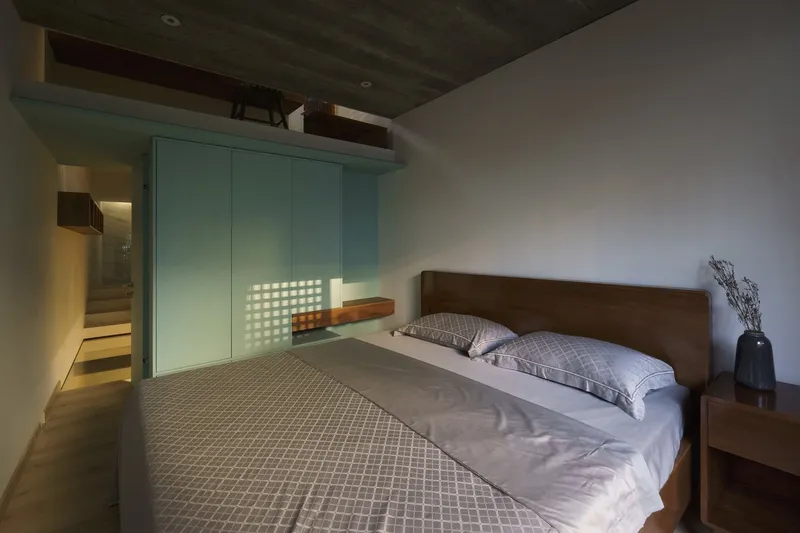 Bedroom with timber headboard, mint green built-in wardrobe, and dark concrete ceiling