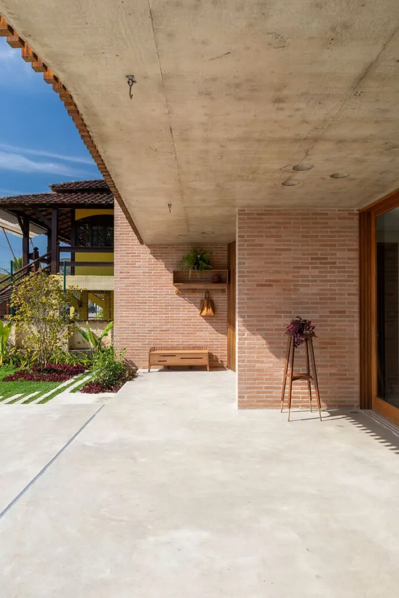 Covered entry terrace with angled brick wall and board-formed concrete soffit above planted beds