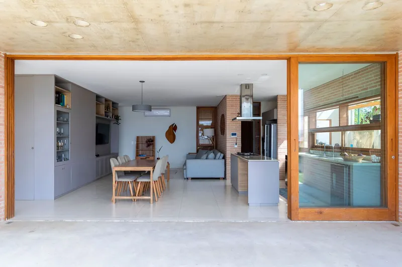 View through open sliding doors from terrace into the dining and living spaces under concrete ceiling