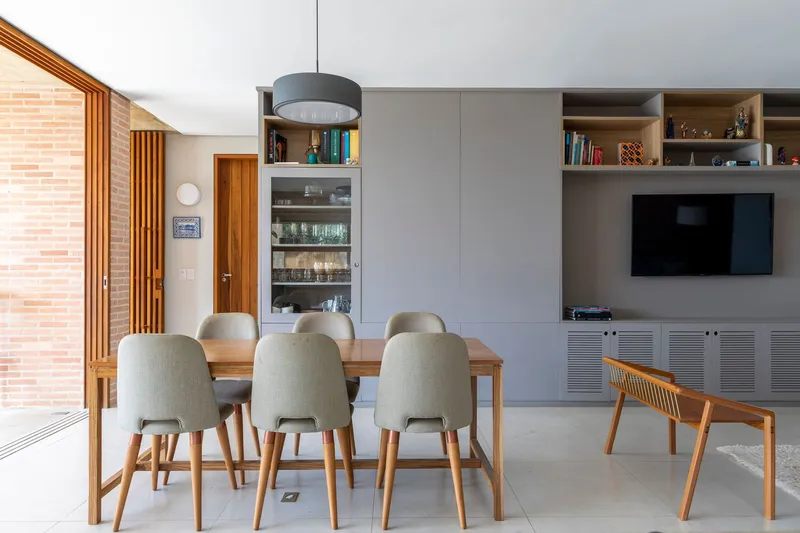 Dining area with timber table and built-in shelving beneath a pendant light and exposed brick wall