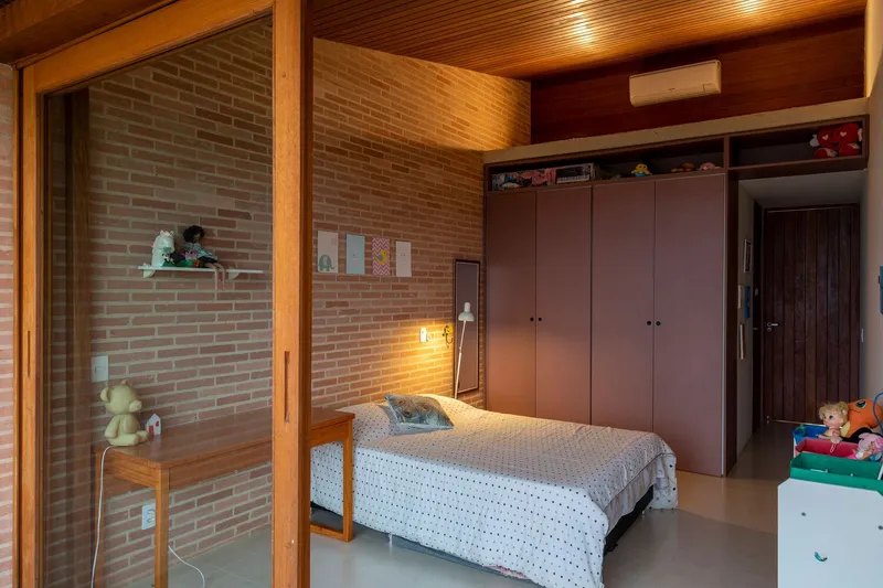Bedroom with exposed brick wall, timber ceiling, and sliding glass door opening to interior courtyard