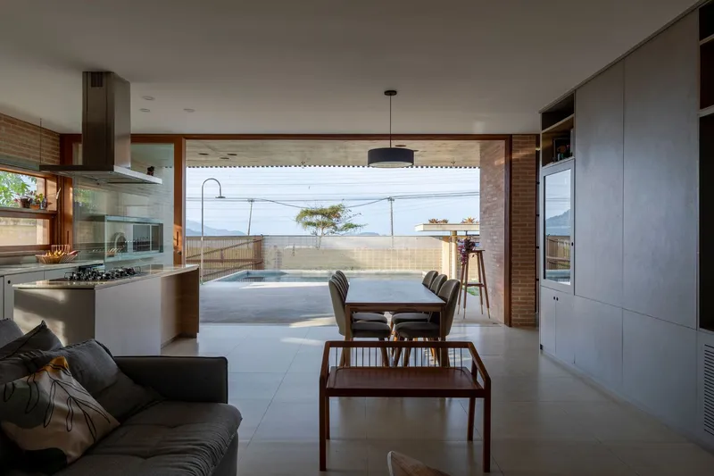 Open-plan living and kitchen space looking through timber-framed opening toward exterior terrace and distant hills