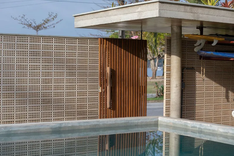 Perforated concrete block wall and timber slat screen surrounding a pool with concrete canopy above