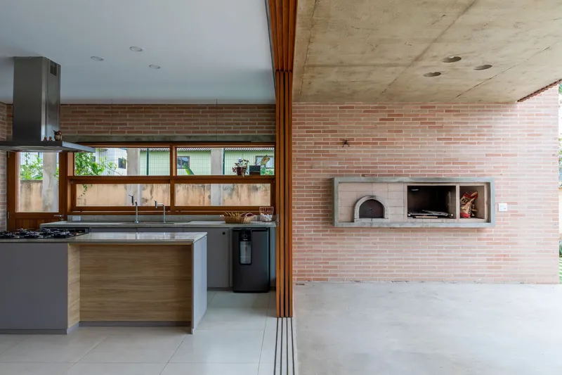 Kitchen with exposed brick wall, built-in pizza oven, and horizontal window above timber cabinetry