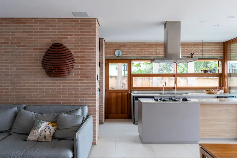 Open living and kitchen area with exposed brick walls and timber-framed glazing to the garden