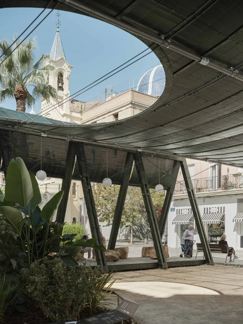 Curved opening in the overhead structure revealing a church bell tower and distant towers beyond