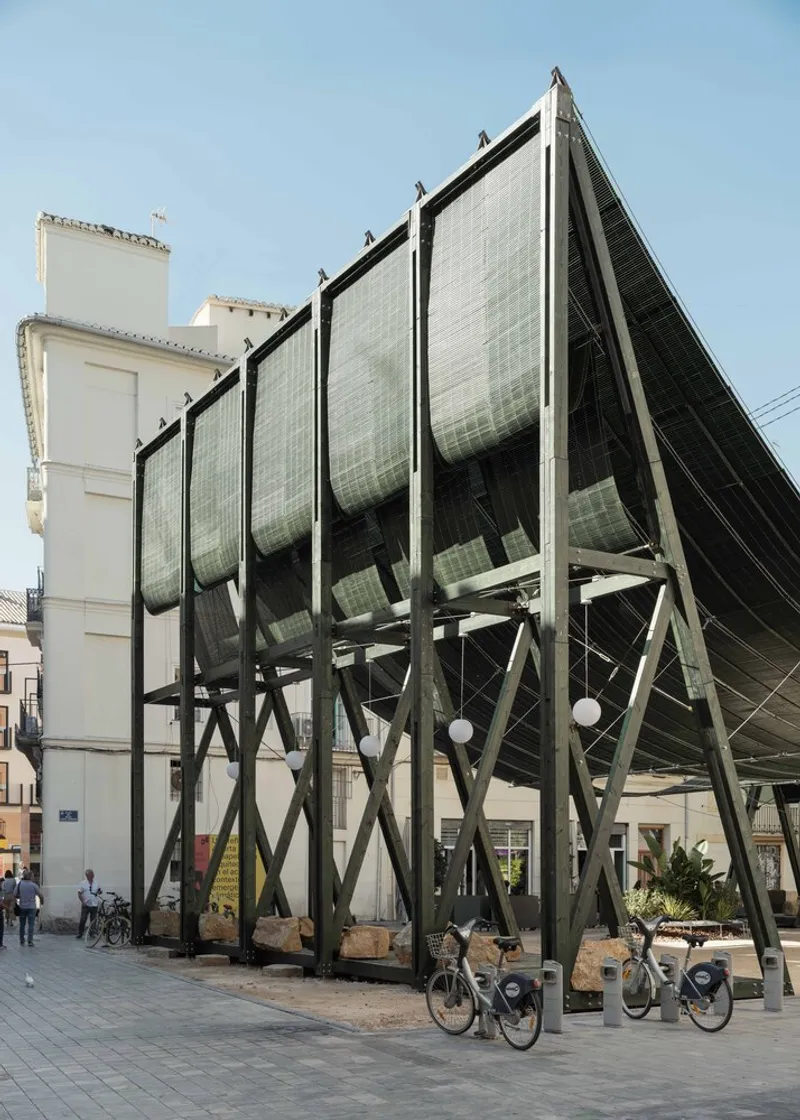 Angled view of the steel frame with vertical mesh panels and shared bicycles below