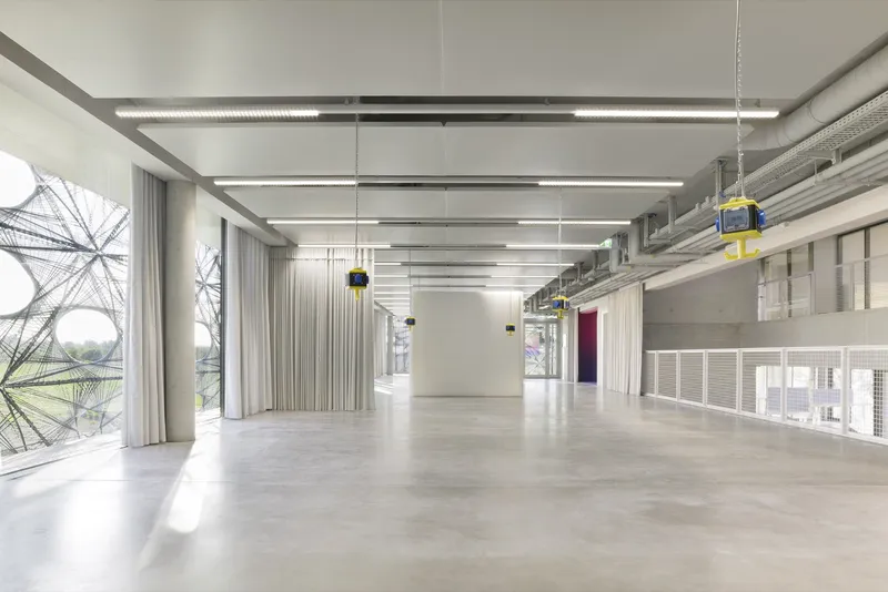 Open floor space with polished concrete flooring and curtained windows overlooking a landscape